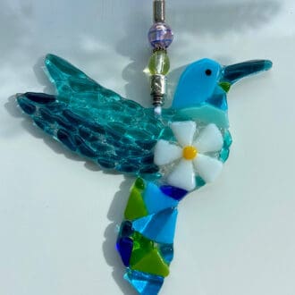 Sun-catcher fused glass hummingbird with daisy design on its breast.