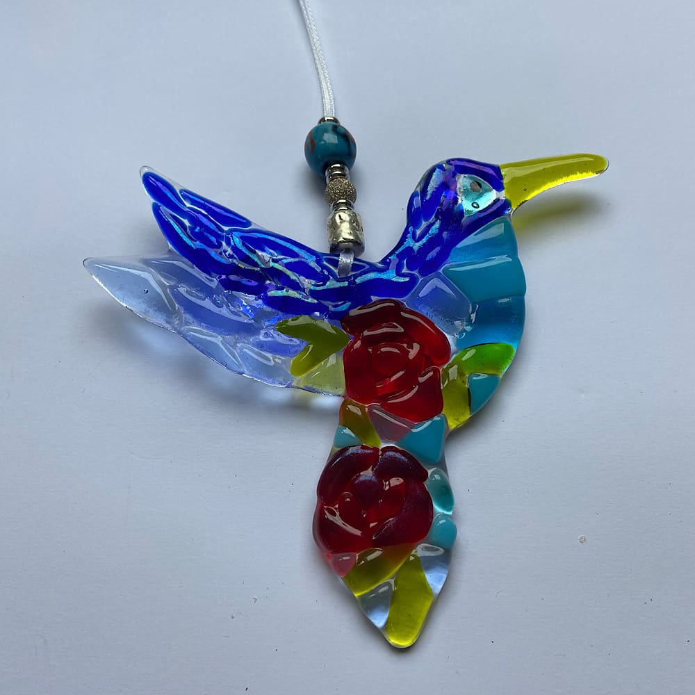 Glass hummingbird sun catcher with rose design element on its breast.