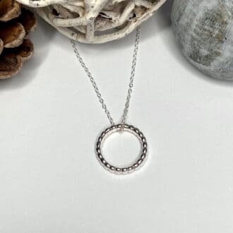 A handmade silver circle necklace with beaded effect