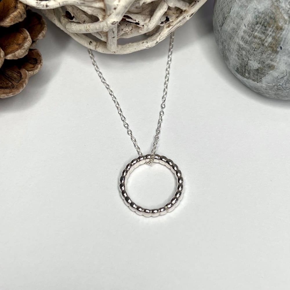 A handmade silver circle necklace with beaded effect