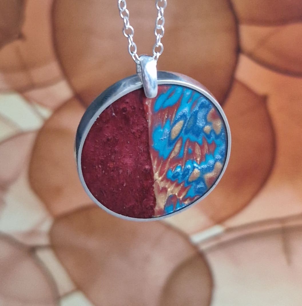 Handmade sterling silver round pendant, inlayed with resin and polymer clay, in shades of terracotta gold and turquoise.