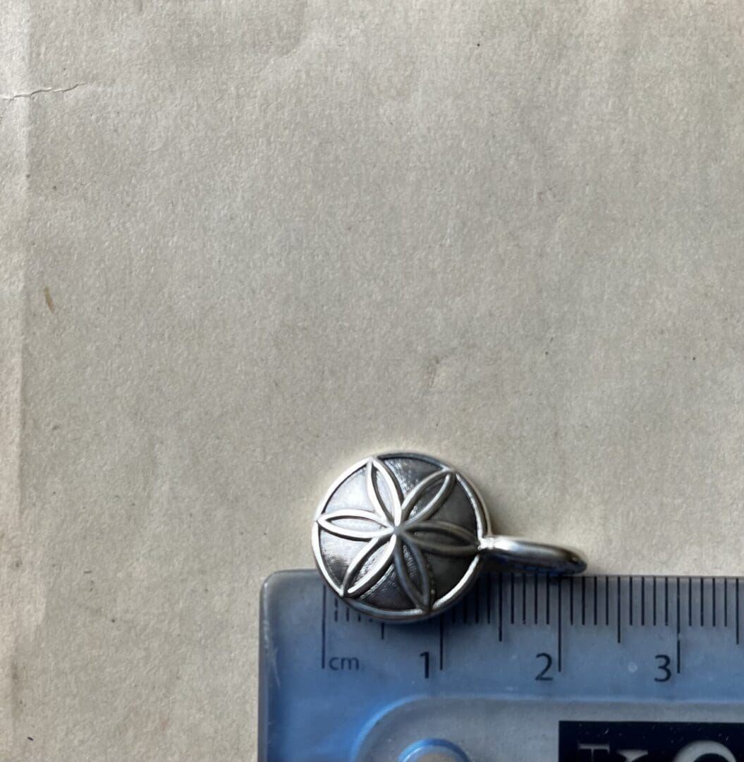 a small pendant with the hexafoil pattern is placed on top of a ruler showing the total height of the piece to be 22mm