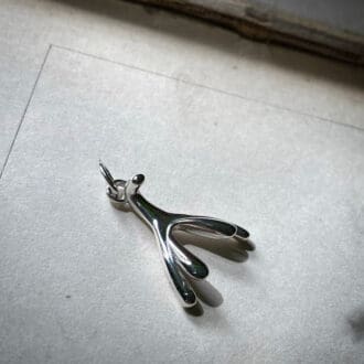 a silver pendant in the shape of the anatomical clitoris