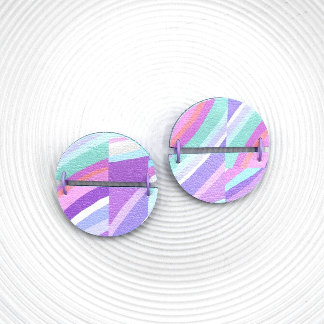 Purple, pink, mint and peach unusual round studs. Decorated with striped faux leather, pastel rainbow . On a white textured plate