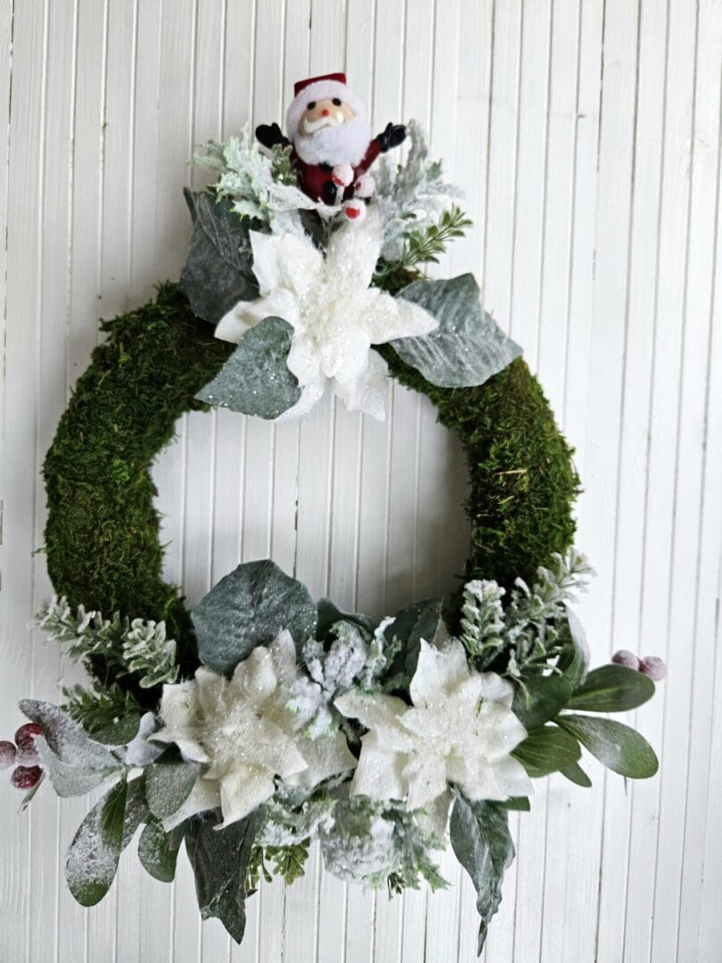 Father Christmas Wreath on a moss base with white sparkly poinsettia