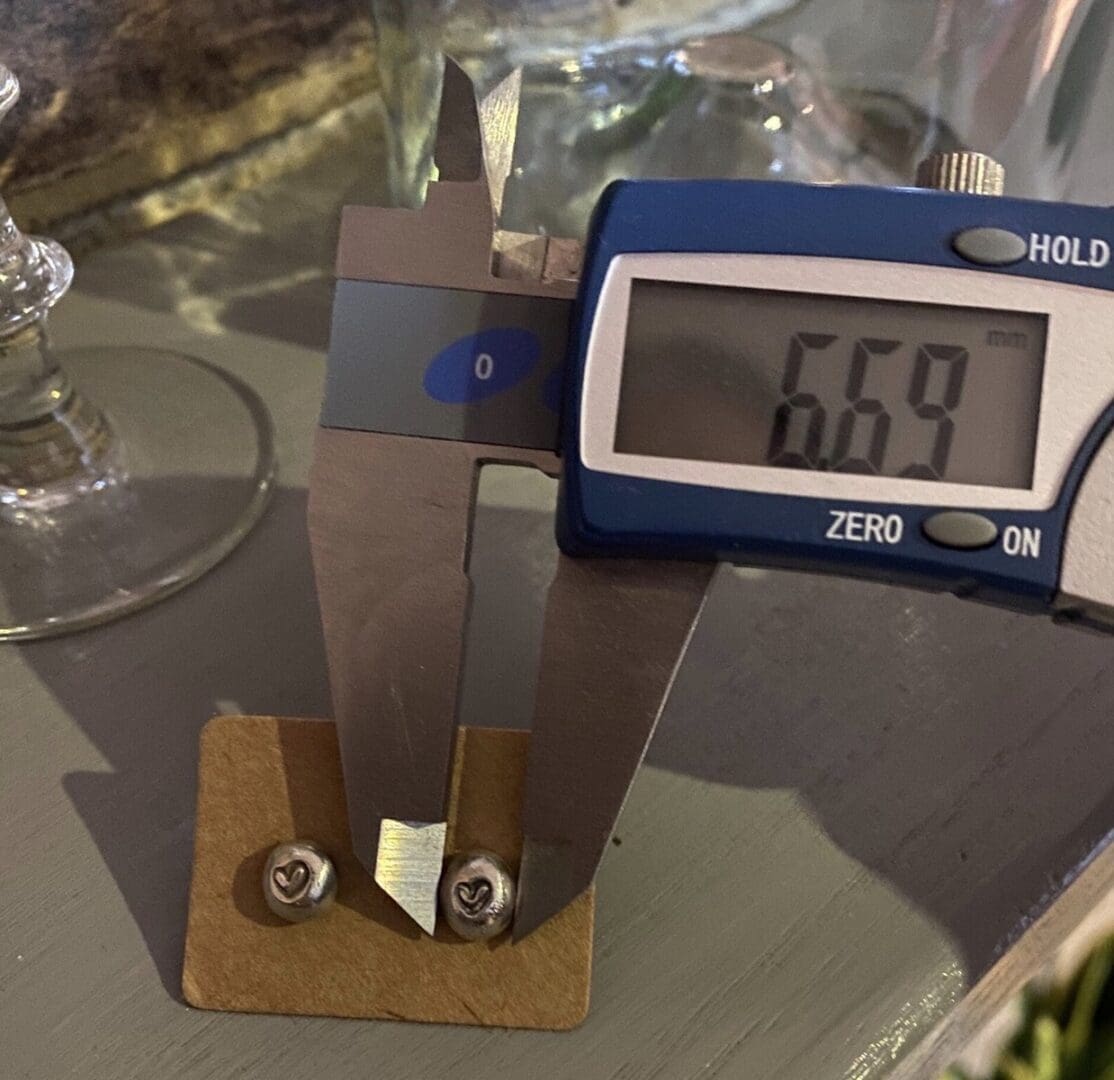 a measuring gauge showing the size of a silver earstud, the digital screen shows 6.69mm