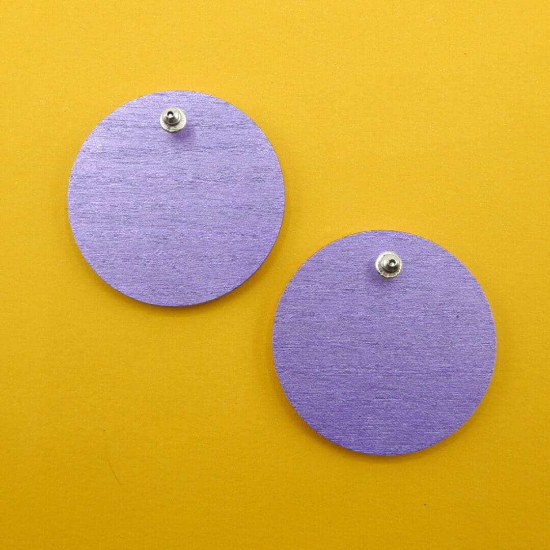 Sowing the reverse of both earrings with their metallic purple paint. Stud post is shown secured behind the wood, hidden between the fabric front and back