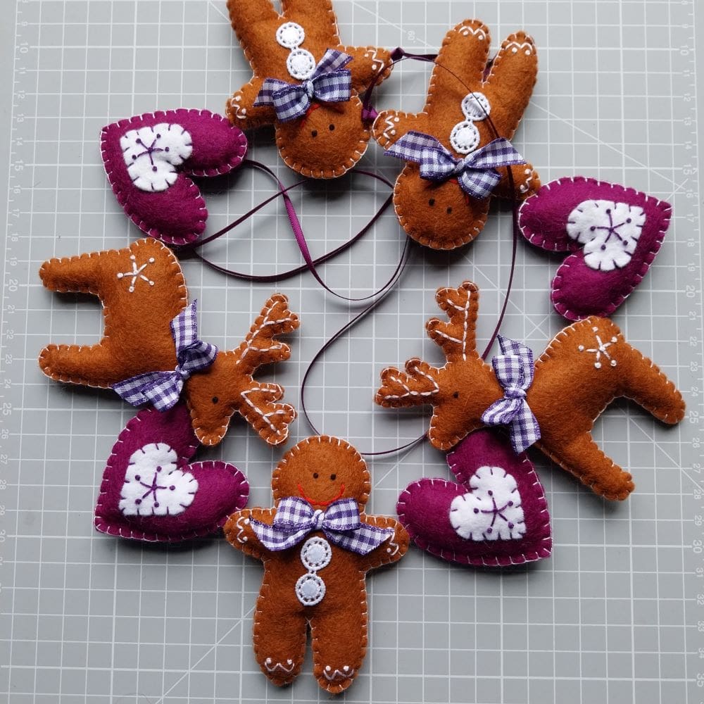 a hand stitched felt garland of gingerbread men, reindeer and embroidered hearts