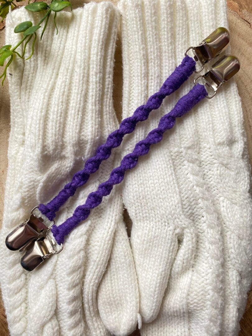 A pair of purple mitten clips made with recycled cotton