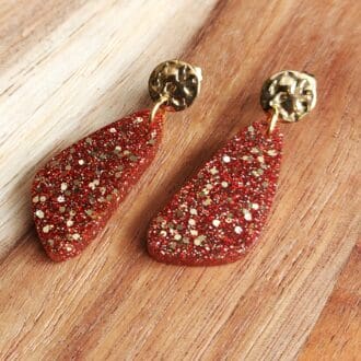 Resin drop earrings handmade with red and gold glitter and topped with textured gold tone stud tops.