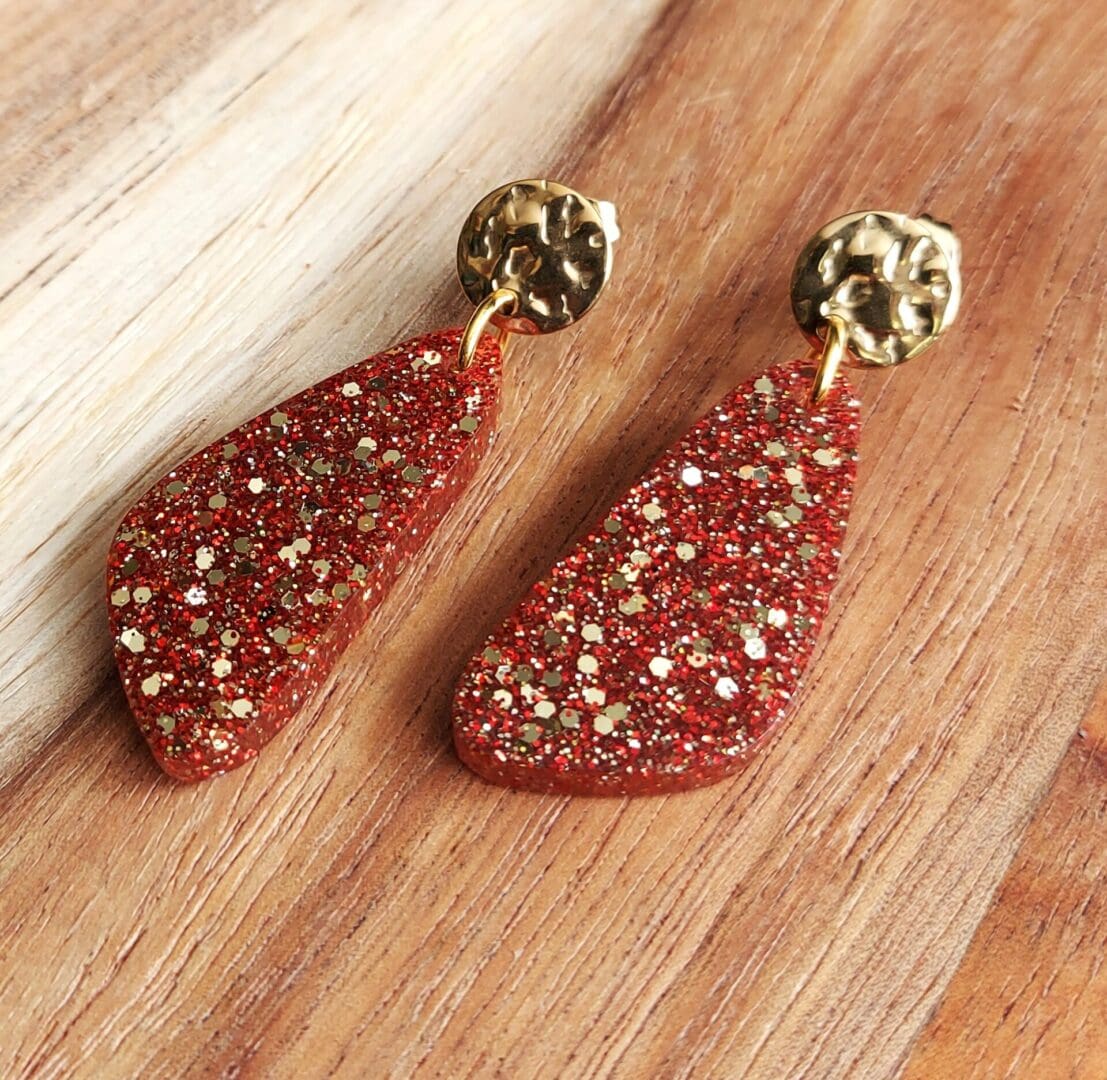 Resin drop earrings handmade with red and gold glitter and topped with textured gold tone stud tops.