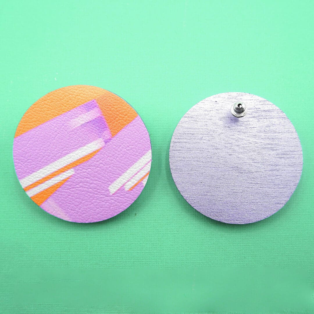 Showing from and back of lilac and orange round stud earrings. The reverse is shown painted in a metallic lavender colour