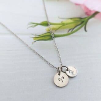 9mm silver disc hand-stamped with a zodiac sign alongside an optional 7mm stamped initial disc, on a silver trace chain necklace