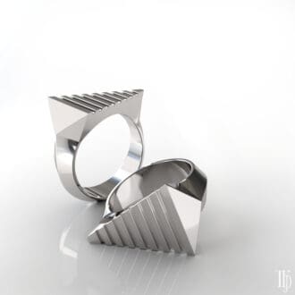 two of the same ring, one is standing up and the other laying flat with its top towards the camera. The rings are faceted with geometric angles