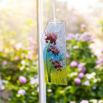 Handmade fused glass lavender suncatcher with purple wildflowers, green meadow background, and textured details, hanging on a white ribbon – 13x5 cm. Perfect for spring decor, Valentine’s gift, or unique thank you gift.