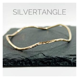 Wavy Hammered Gold Bangle sitting on a slate