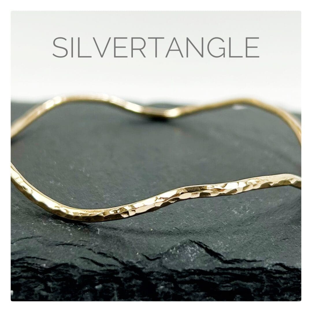 Wavy Hammered Gold Bangle sitting on a slate