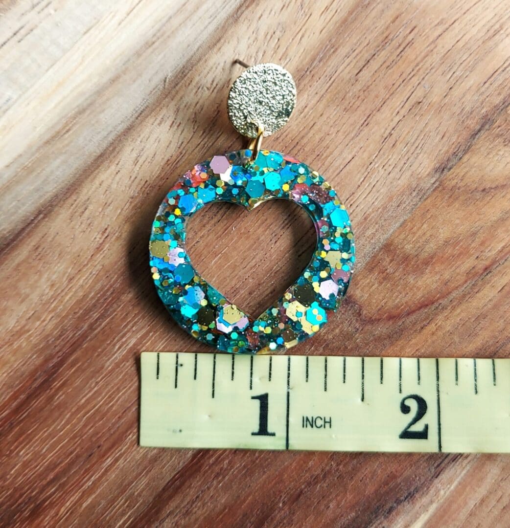 Circle drop hoops with heart cu touts made in rainbow glitter resin. Hung from textured gold tone stud tops.