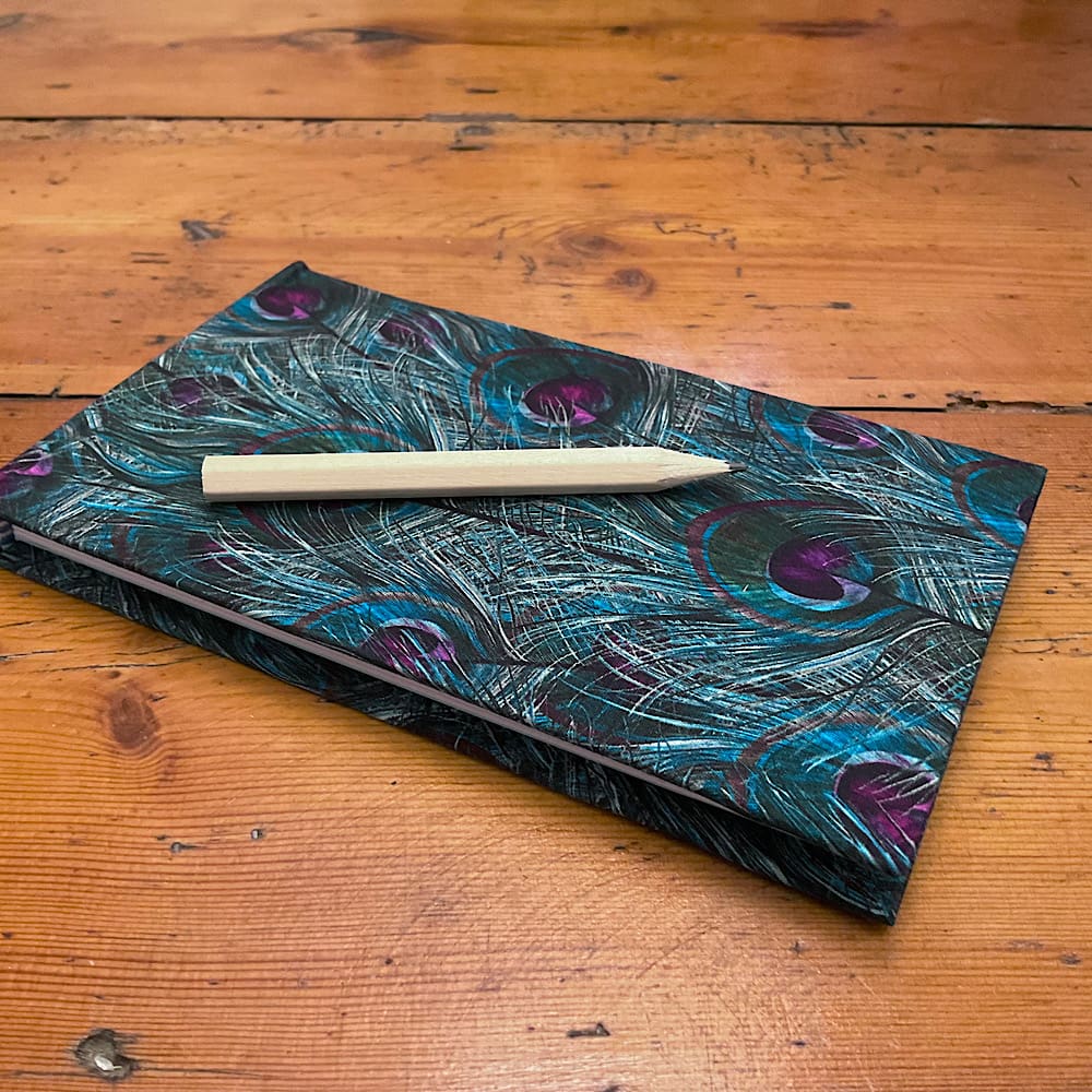 Handmade Jotter Notebook filled with plain paper covered in a peacock feather design fabric