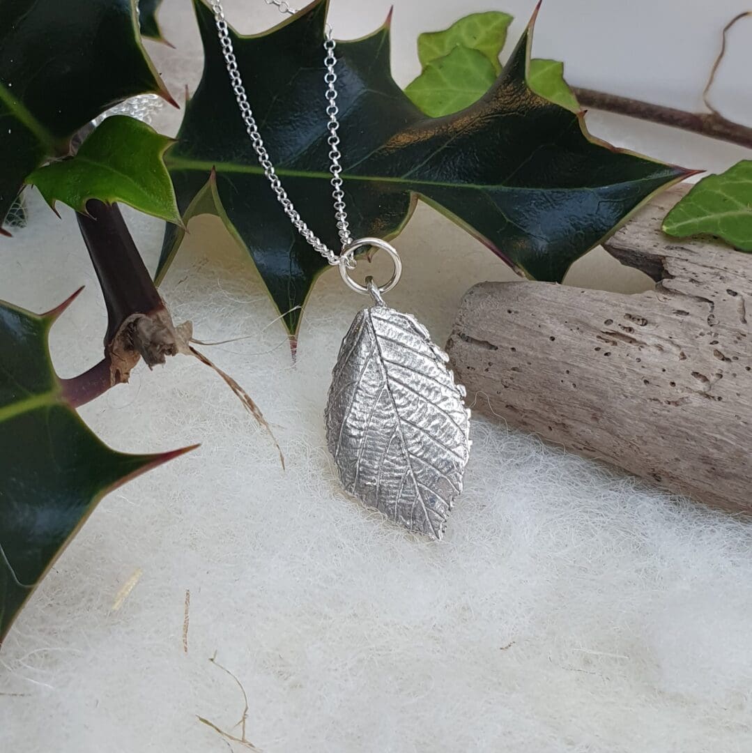 A fine silver rose leaf pendant hanging on a silver chain