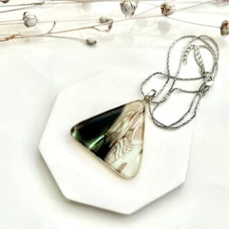 A fused glass pendant in mono chrome colours with a touch of sparkle from the dichroic glass. The pendant is a triangle shape and has a stainless steel chain and bail.