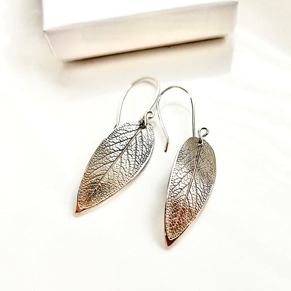 A pair of fine silver long drop earrings in a sage leaf design with sterling silver ear wires. The earrings are displayed on a plain White background.