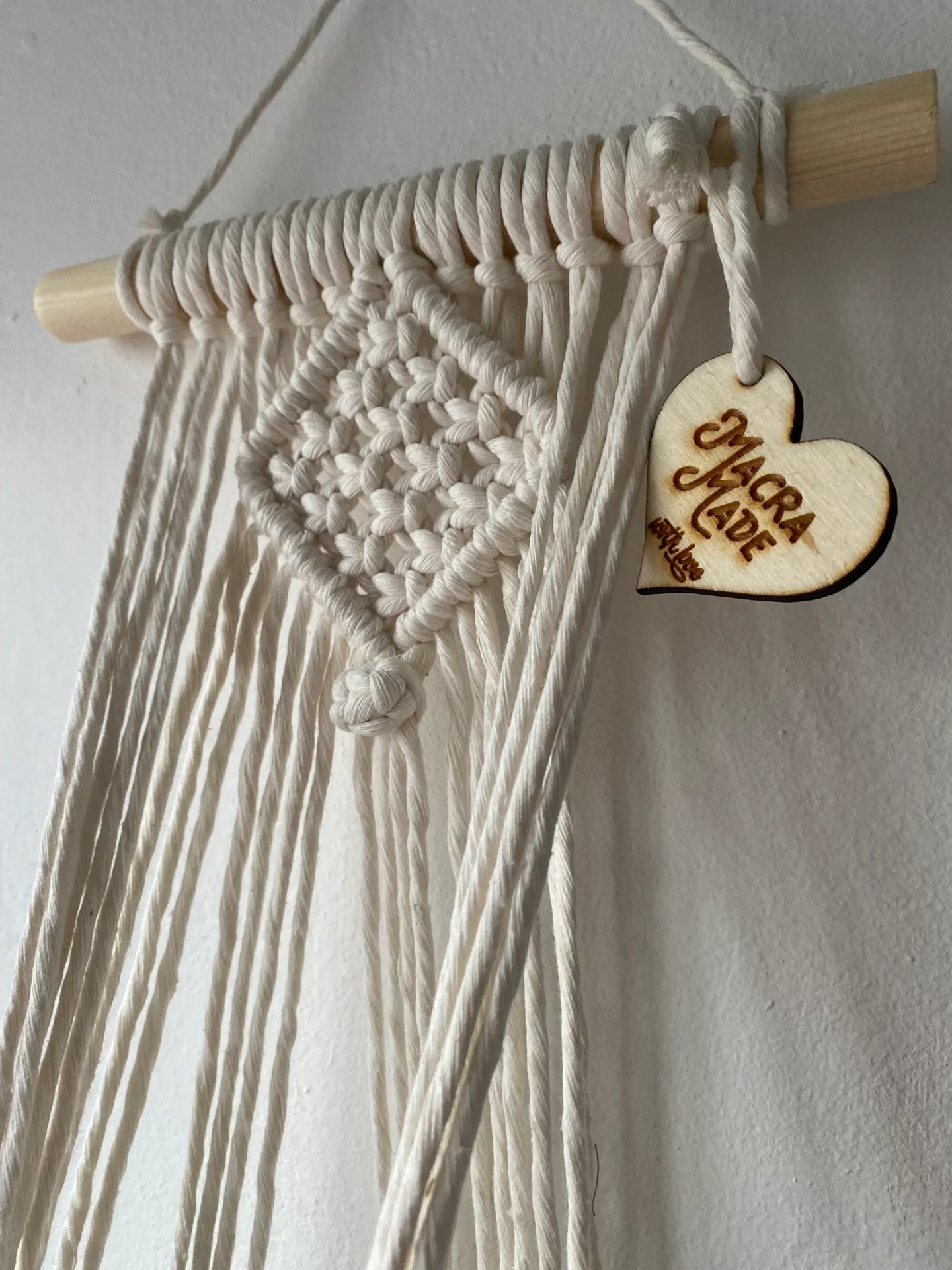 Macrame wall hanging indoor plant holder, made with natural recycled cotton on a wooden dowel.