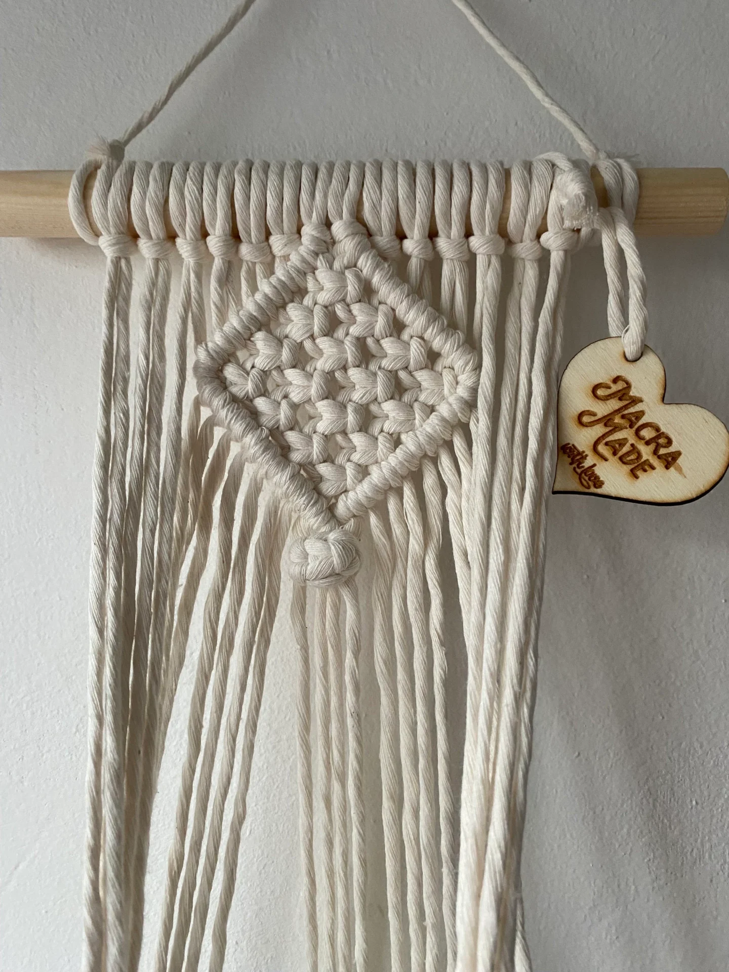 Macrame wall hanging indoor plant holder, made with natural recycled cotton on a wooden dowel.