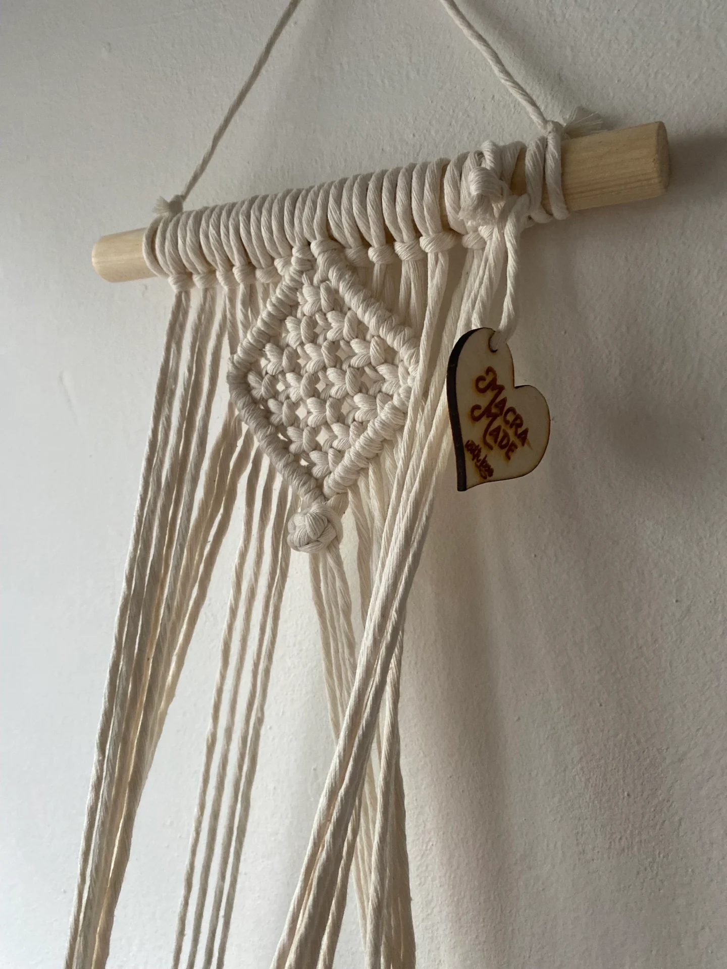 Macrame wall hanging indoor plant holder, made with natural recycled cotton on a wooden dowel.