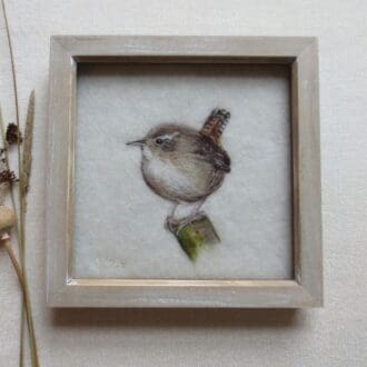 A small brown wren bird perched on the end of a green twig. The wren is facing forward but looking towards the left.