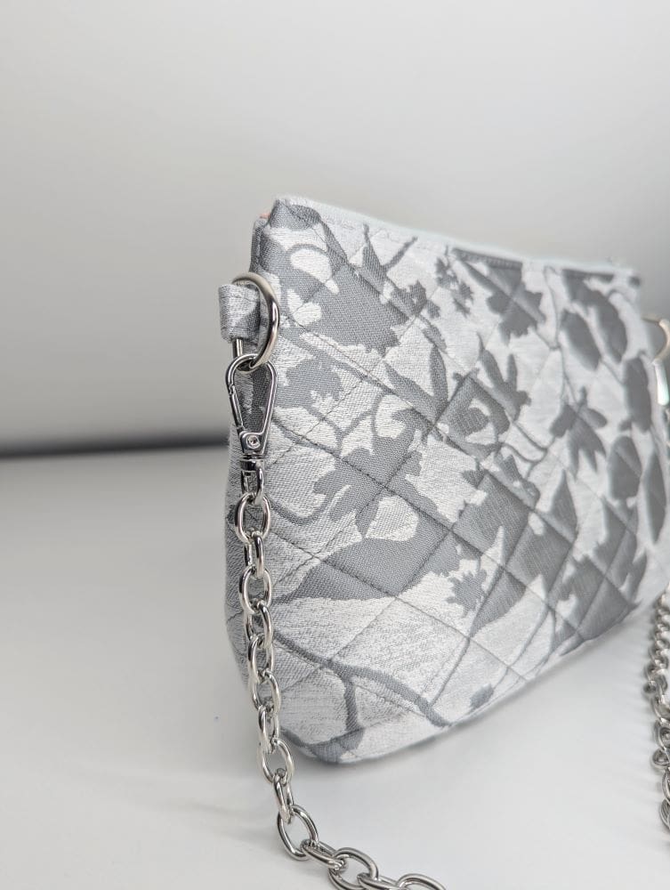 Elegant evening bag with quilted floral design and a silver chain strap.