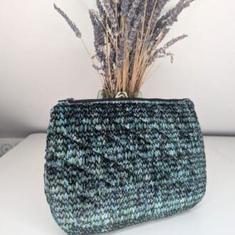 a green and black woven fabric zipper pouch in front of dried lavender