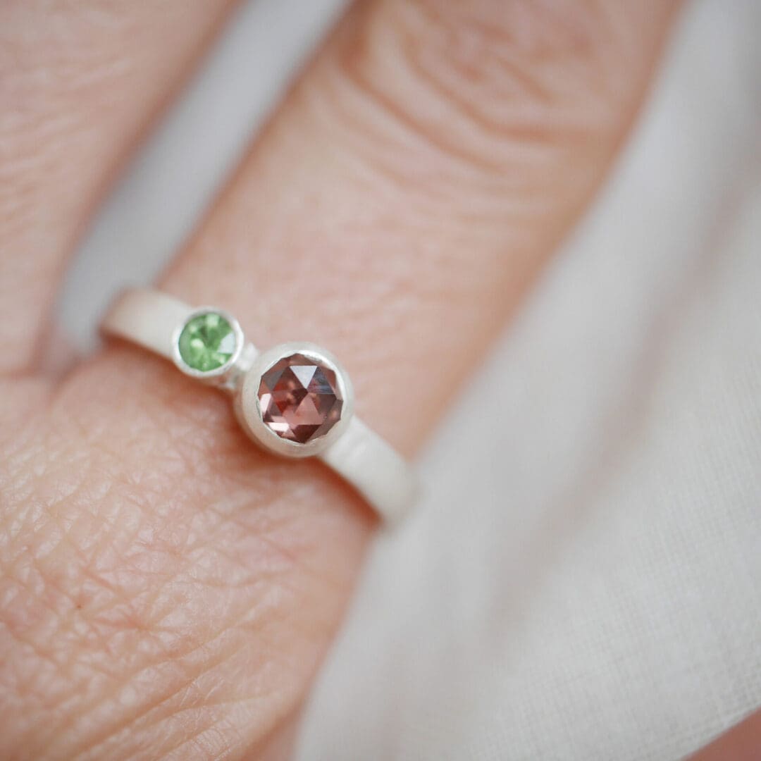 Peach Garnet and green zircon argentium silver ring on a hand