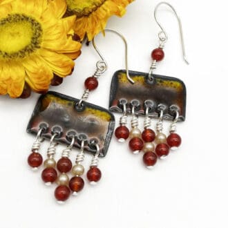 enamel earrings in shades of brown, gold and yellow decorated with red and pearl beads for a boho look