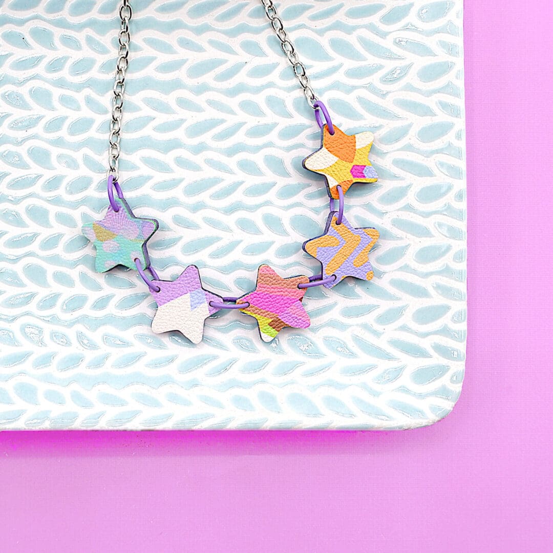 Overhead photo of pretty colourful 5 star necklace, Stars in a range of pastel colours: pink, lilac, turquoise, peach and yellow