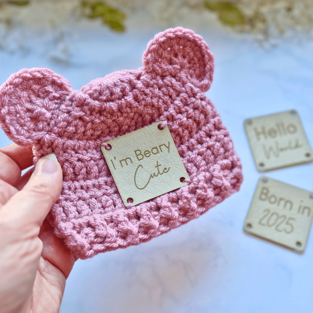 Handmade Crochet bear hat with leather patch, a choice of I'm Beary Cute, Born In 2025 or Hello World, pictured in pale rose