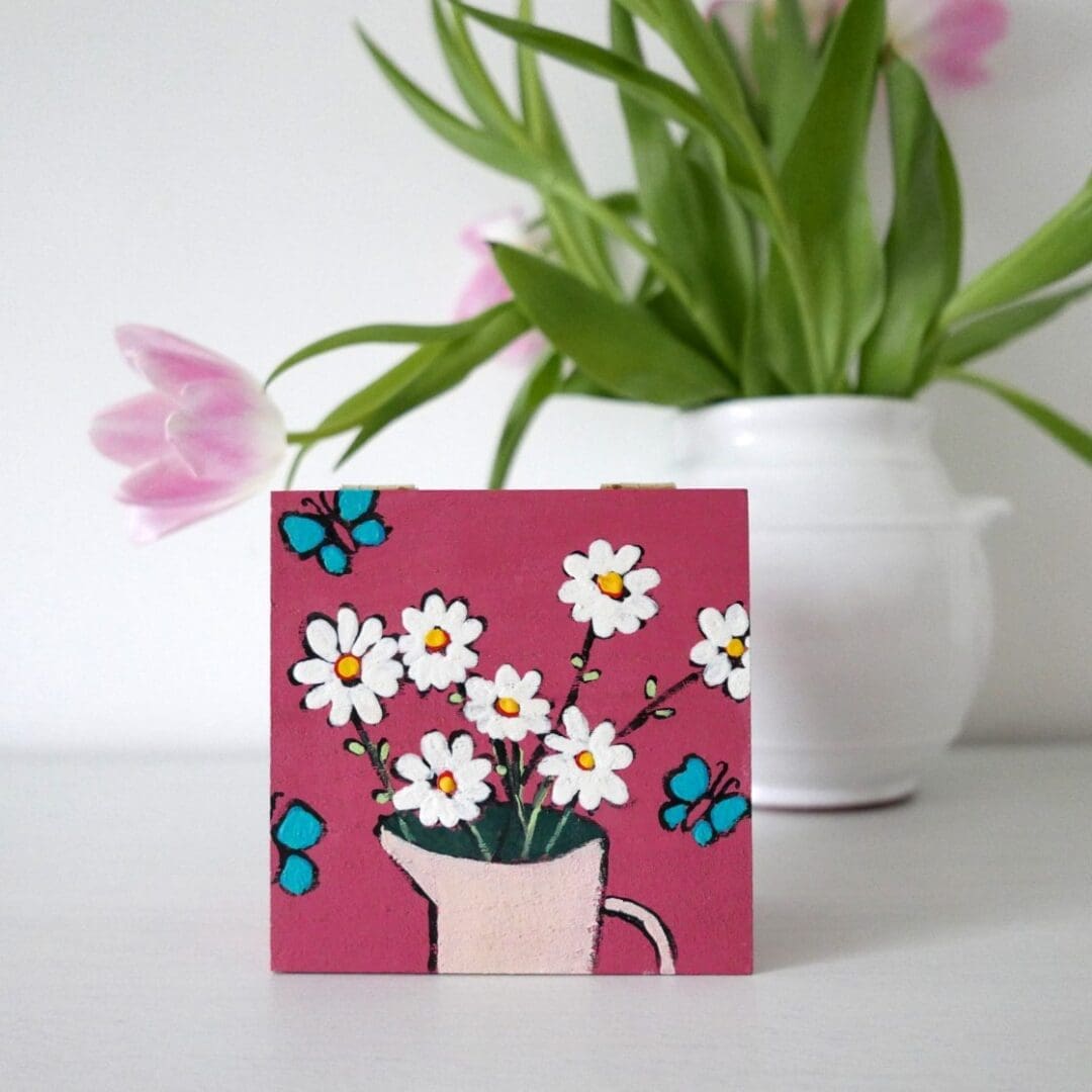 Dusty pink jewellery box, hand painted with white daisies, in a pink vase with turquoise butterfliues