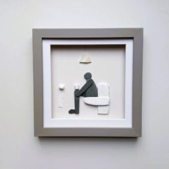 framed picture of man sitting on toilet made from pebbles