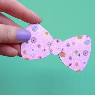 Pretty pastel watercolour polka dot brooch. Shown held in hand against a mint background