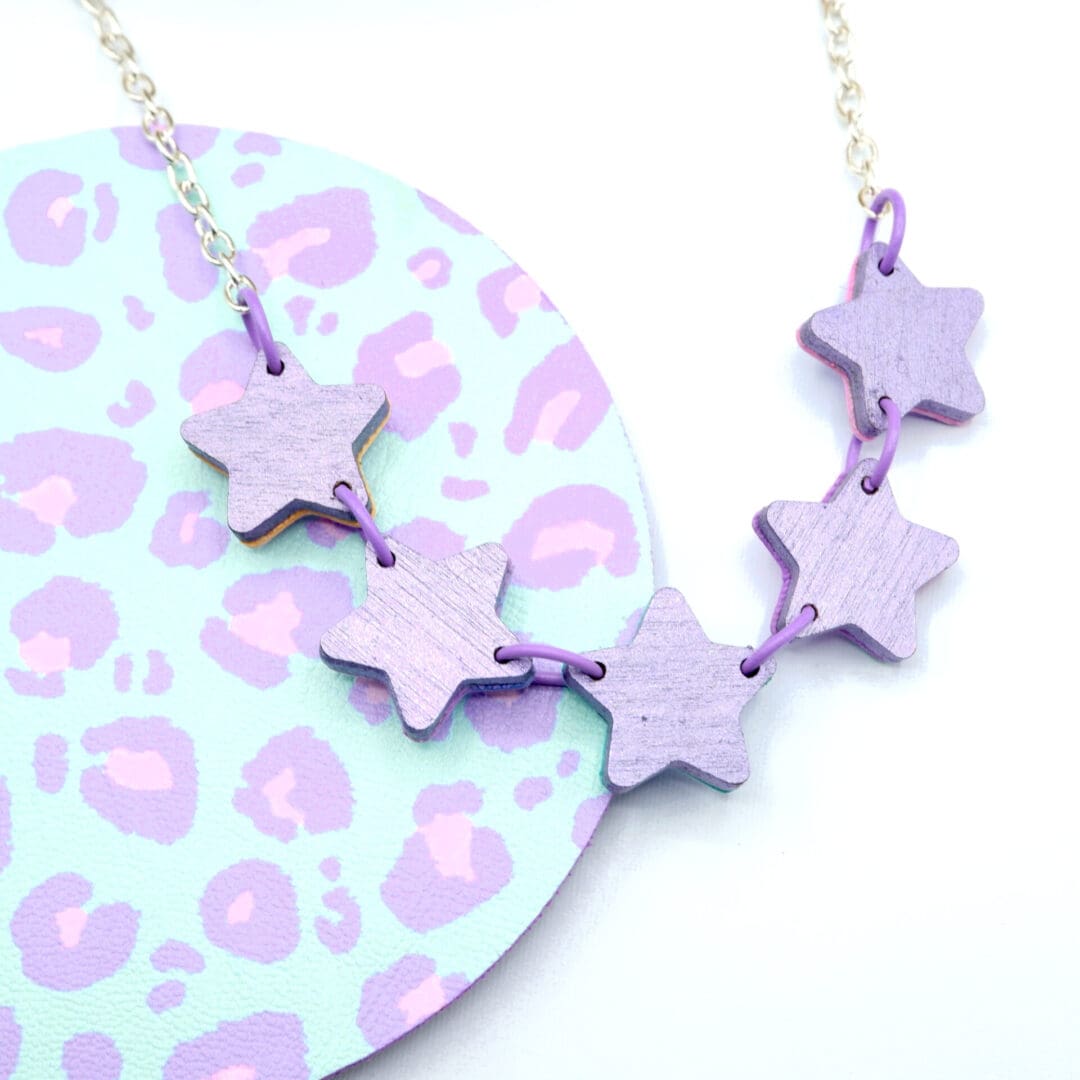 Reverse of dinky star charm necklace showing the pretty metallic purple painted wood back