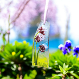 Handmade fused glass lavender flower suncatcher with vibrant purple and green details, perfect for home decoration or as a thoughtful gift. Inspired by nature, this UK-crafted piece adds a touch of springtime charm to any sunny window or garden setting. Unique artisan craftsmanship with a delicate ribbon hanger for easy display.