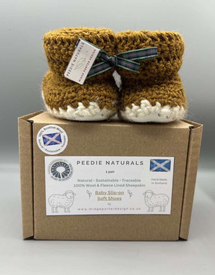 Pair of 100% Scottish Wool Baby soft shoes booties. Presented with a tartan ribbon and box. Handmade in Scotland by Midge Porter Design as part of the 'Peedie Naturals' Clan colours range.