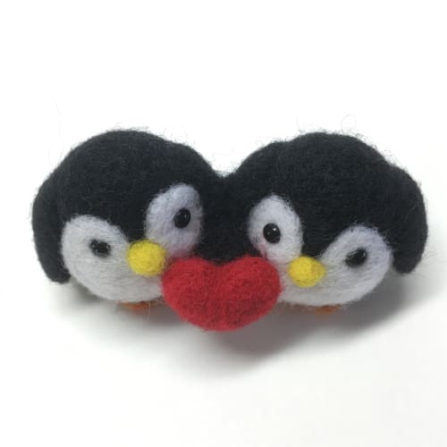 Needle-felted penguin couple viewed from above, highlighting their round shapes and close connection.